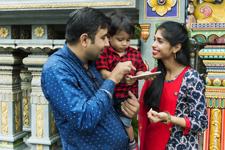 印度父亲向儿子展示在印度母亲身边使用手机