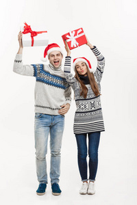 圣诞节概念年轻可爱的夫妇举行礼物孤立的白色灰色背景