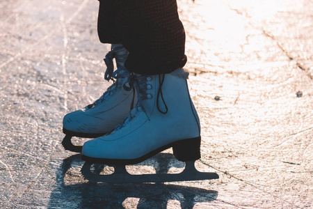 一个年轻的女孩站在冰封的池塘上的冰鞋里。 不错的柔和日落光。