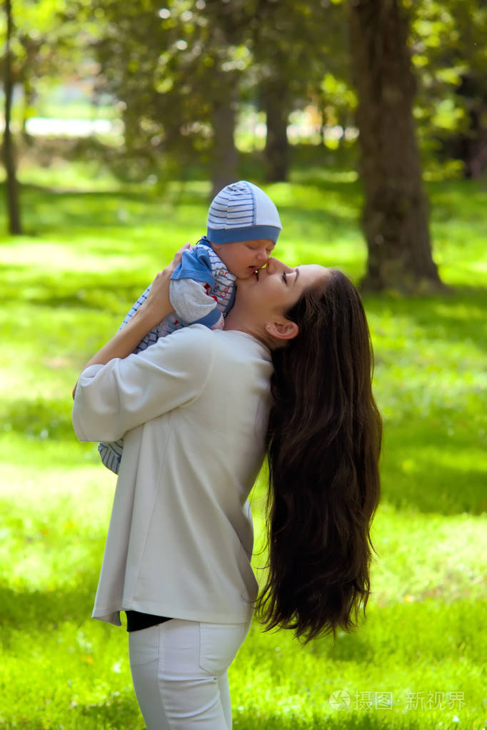 一个带着一个小孩子的女人正在阳光明媚的春天森林里散步