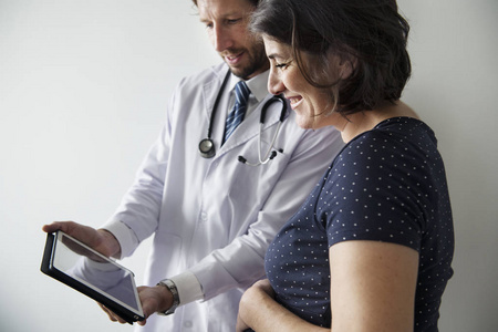 医生在数码平板电脑上给孕妇看胎儿的照片