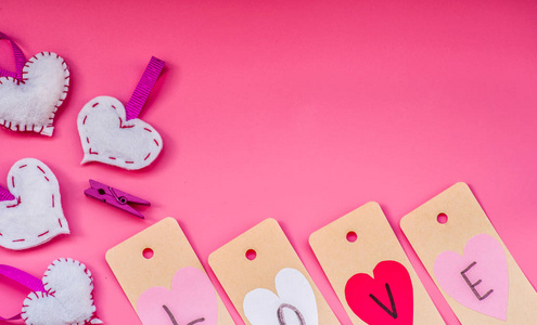 情人节假期。可爱的手在粉红色的背景下为情人节做了装饰品。我爱你标签和折纸心