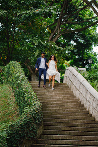 白天在公园的石阶上有一对不同种族的恋人。 一个印度男人正在嫁给一个中国女人，他们高兴地跑下楼梯。