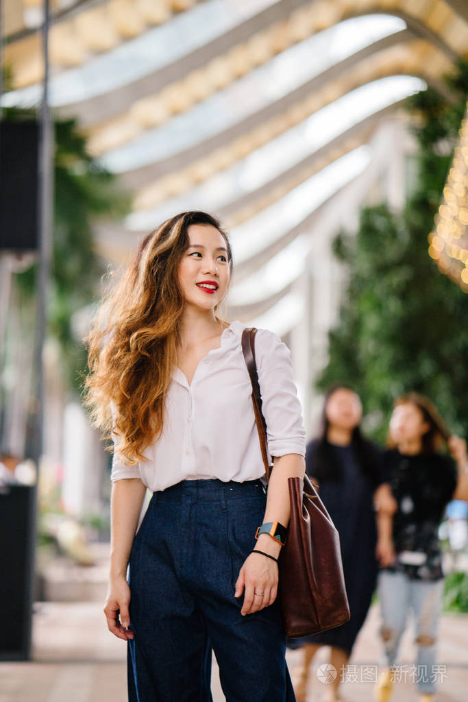 她是中国人(新加坡人),穿着专业优雅. 她很放松,对着相机微笑.