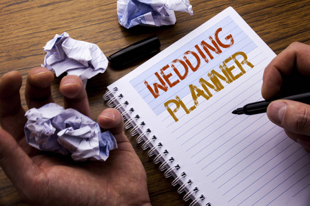 字, 写婚礼策划人。关于婚姻准备的概念写在笔记本记事本笔记纸上的木质背景与折叠纸意义思维的想法。人手和标记