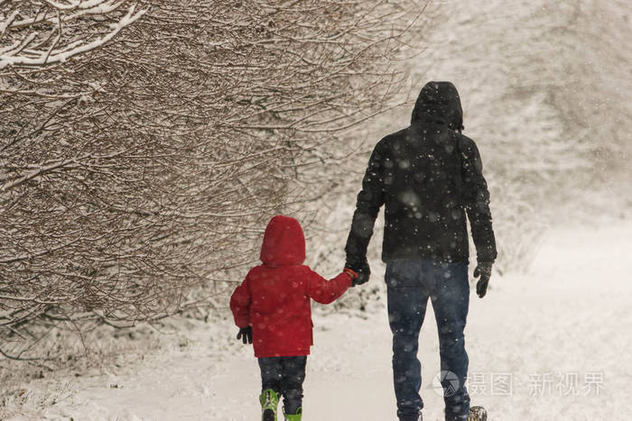 在一场大雪中, 父亲和小女儿在森林公园散步