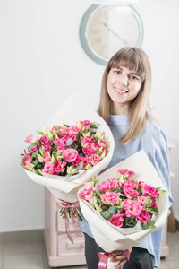 两朵花花束。阳光明媚的春天早晨。年轻快乐的女人拿着一束美丽的粉红色洋或桔梗在她的手中。送给一个微笑的女孩