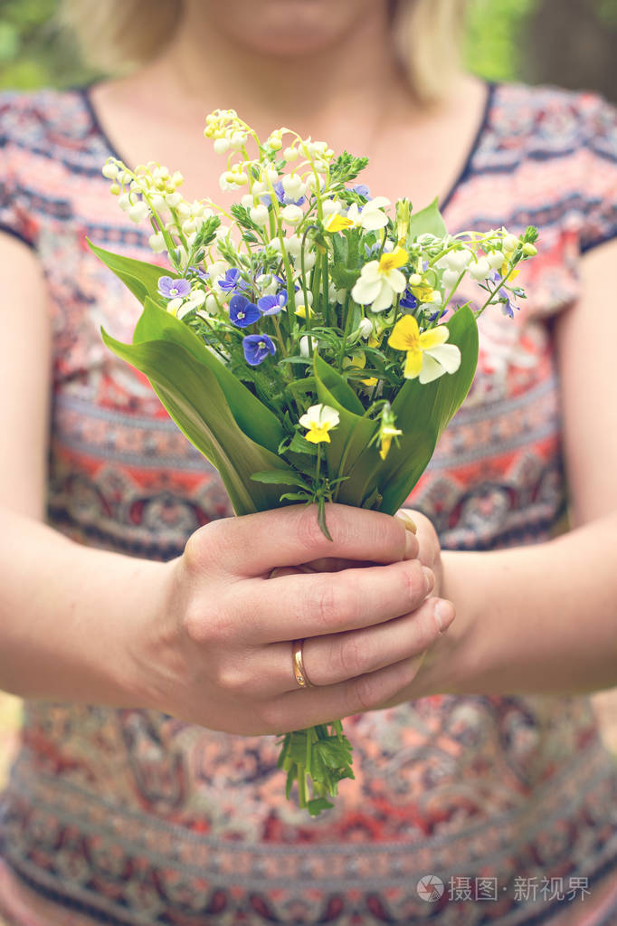 一束百合花的山谷和森林紫罗兰在一个女人的手