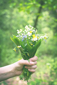 一束百合花的山谷和森林紫罗兰在一个女人的手照片