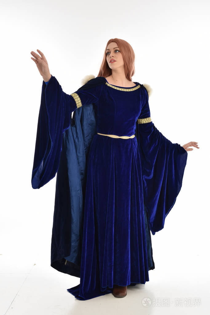 穿着蓝色天鹅绒中世纪长袍和毛皮斗篷的长发妇女的全长