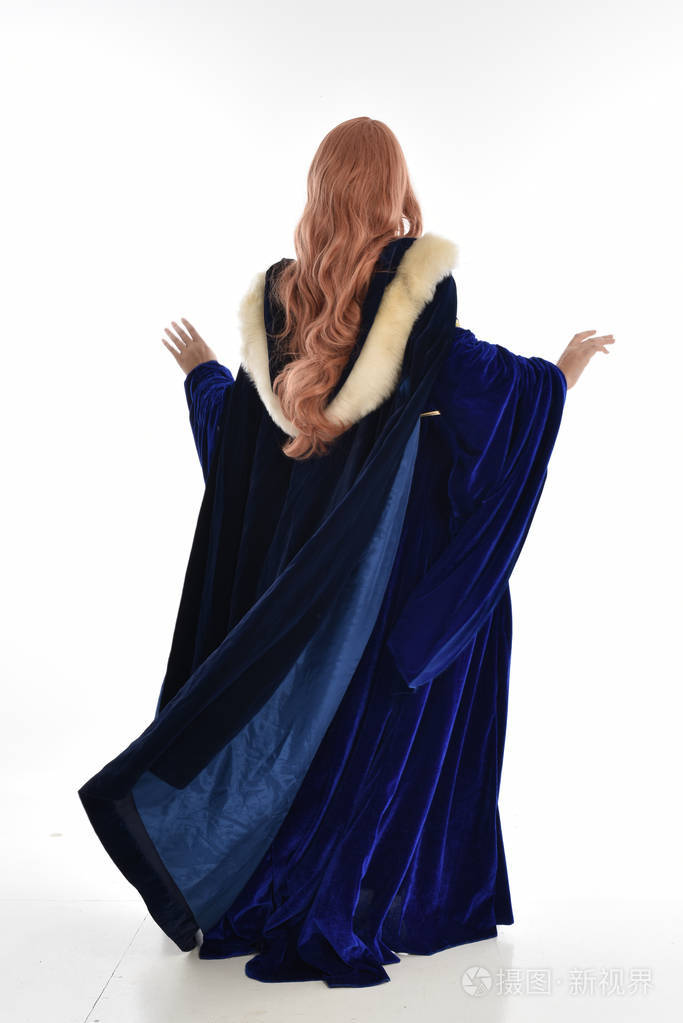 穿着蓝色天鹅绒中世纪长袍和毛皮斗篷的长发妇女的全长