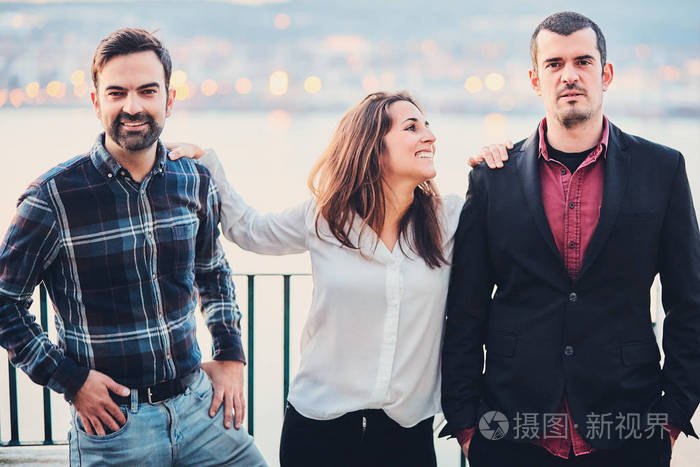 朋友们在夜晚的城市和河流的背景下大笑.现代青年生活方式