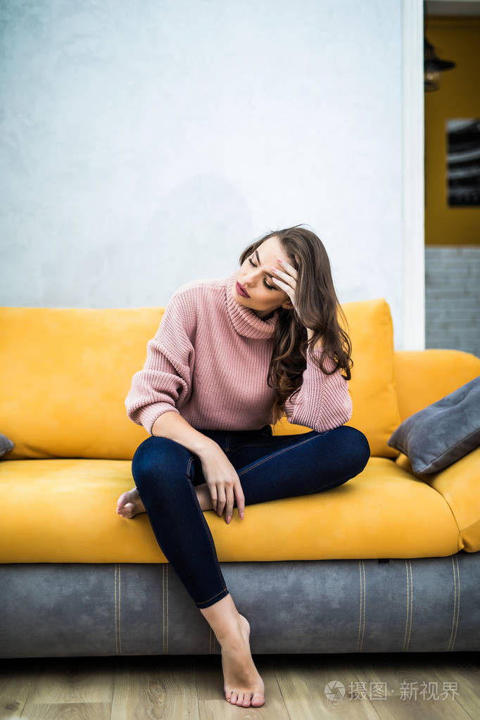 一个疲惫的邋遢女人坐在沙发上的照片在家里.女孩看电视新系列.