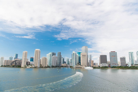 鸟瞰迈阿密摩天大楼与蓝色多云的天空, 白色小船航行在迈阿密市中心旁边。迈阿密豪华物业, 现代建筑和游艇, 成功的生活理念
