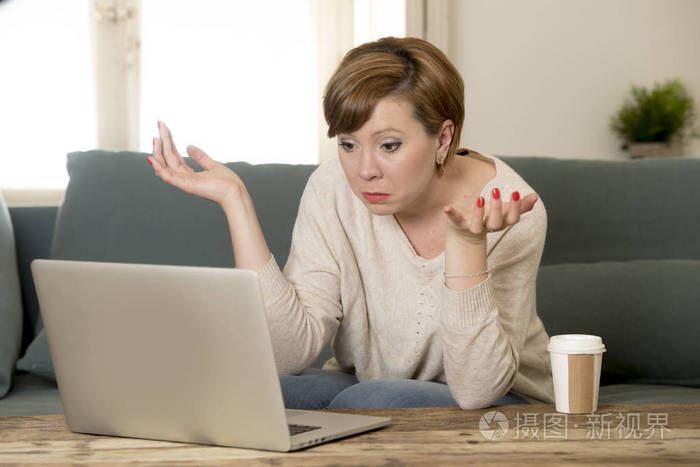 年轻有吸引力和忙碌的女人在家里沙发沙发做一些笔记本电脑工作压力看