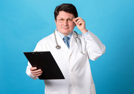 一位蓝色背景的男医生的肖像. 中年男人.照片