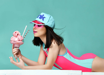 粉红色帽子的年轻妇女吃草莓冰淇淋甜点在现代浅蓝色