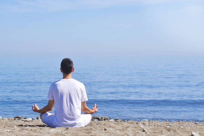 年轻人在海上海洋海滩上以莲花姿势冥想和谐和沉思男孩