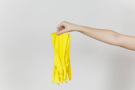 女性手的特写拿着一双黄色的橡胶手套和乳胶, 用于清洗和清洗在白色背景下隔离的盘子。清洁用品的概念。复制广告空间