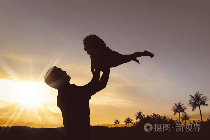 快乐的父亲和小女孩在夕阳下一起玩耍的剪影