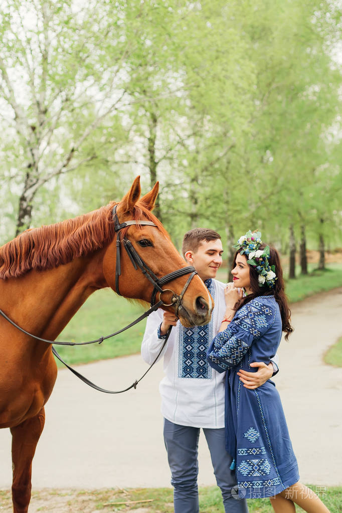 男朋友搂着女朋友的腰第二只手牵着马做缰绳