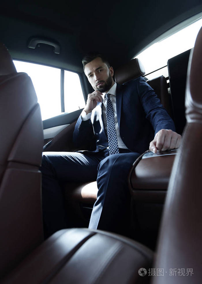 成功的商人坐在车的后座