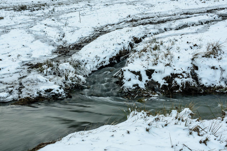 冰泉融化春季解冻 春天的小溪在田野上流着融化的雪照片