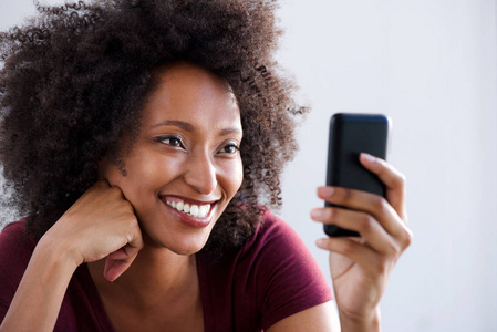 使用智能手机的快乐年轻非洲女人的特写肖像。