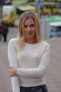 穿着白色毛衣的漂亮年轻女性在街上摆姿势
