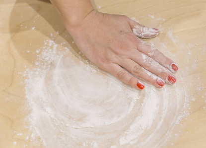 女性手在面团上搓面粉.与模糊效果照片