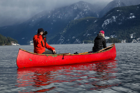 几个朋友坐在一艘木制独木舟上，在一个被加拿大山脉包围的入口划水。 在加拿大温哥华北深海湾附近的印度手臂上。