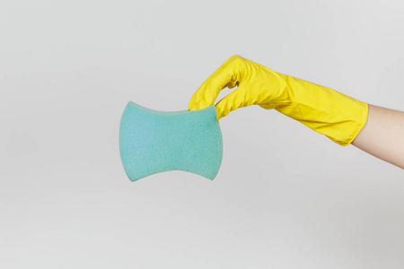 女性手的特写在黄色手套水平举行蓝色大海绵为清洗和洗涤盘子被隔绝在白色背景。清洁用品的概念。复制广告空间
