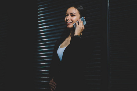 成功的女企业家穿着正式服装，与同事进行移动对话，讨论如何通过现代智能手机设备解决商业问题，站在复印空间附近的户外