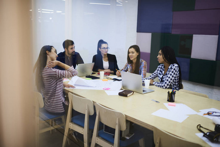 年轻的团队有才华的员工在与男性执行经理的工作会议上解释想法。在会议上的合作中，有经验的设计师分享创造力。