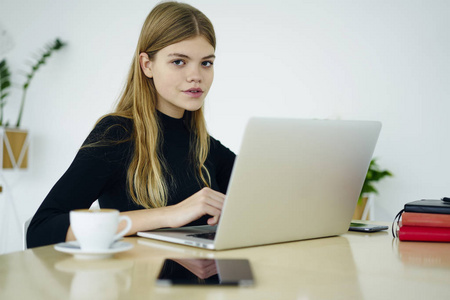 一半长度的美丽女经理坐在笔记本电脑设备连接无线互联网和工作在办公室内部。拥有现代电脑的漂亮文案