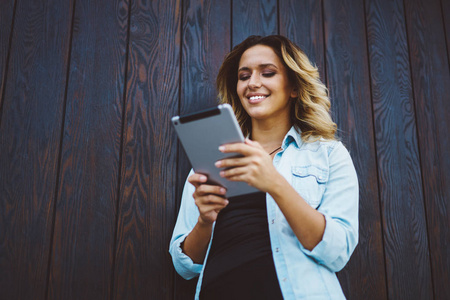 在数字平板电脑上与社交网络上的追随者聊天时，一位年轻的微笑女性在闲暇时在城市环境中使用技术
