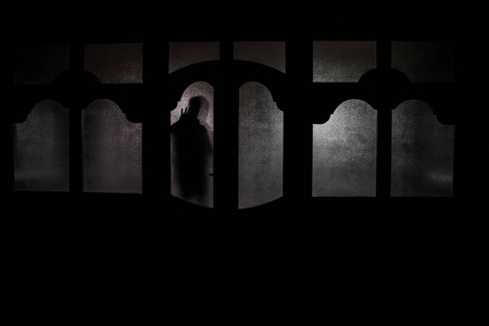 一个未知的影子身影在门通过一个封闭的玻璃门的剪影.