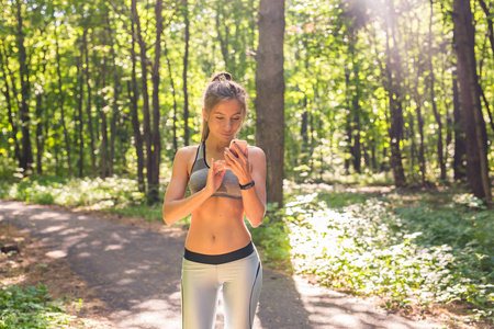 年轻运动员妇女检查健身进展她的智能手表。女性跑步者使用健身应用来监控锻炼性能