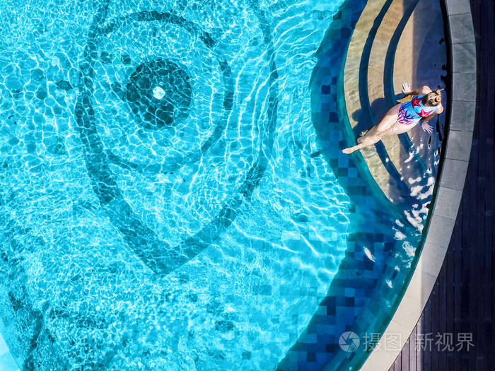 有一个可爱的身材游泳和享受放松在酒店游泳池在她的夏季周末
