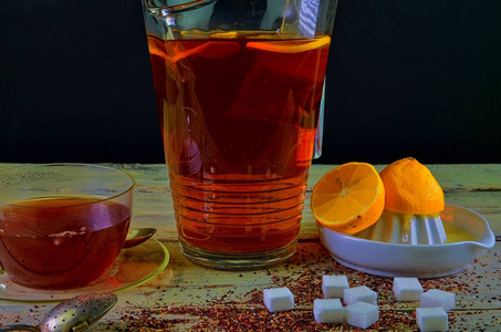红茶, 一杯红茶, 手工挤压柠檬。一壶红茶和一大块糖。深色图像