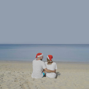 圣诞美丽的海滩情侣戴着圣诞老人的帽子在夏日的阳光下相爱在旅游假期在热带旅游目的地寒假