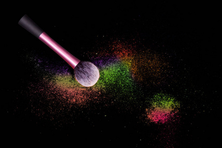 彩色化妆眼影粉在黑色背景与粉红色刷子.照片