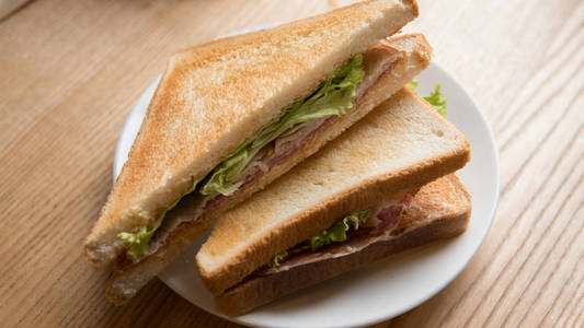 在烤面包的三明治上, 肉馅躺在白色盘子特写上。千禧食品