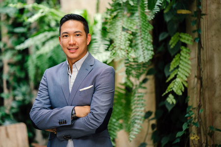 一个英俊的年轻聪明的中国亚洲男人的肖像,穿着西装,微笑着站在绿色的