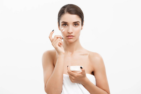 美容青年护肤概念-关闭美丽的白种女人脸肖像涂抹一些奶油她的脸.