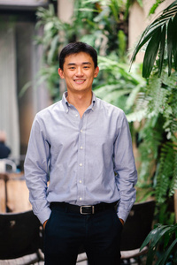 中国工商一位英俊,年轻,聪明的中国亚洲男人穿着西装,微笑着站在绿色