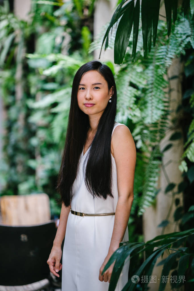 一位年轻漂亮的中国职业女性站在未来建筑上的肖像她以轻松的方式微笑