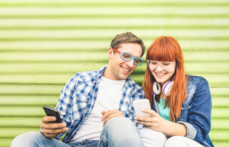 快乐的年轻夫妇玩手机智能手机在老式的垃圾位置友谊概念与时髦的好友连接新技术千年一代在线交友