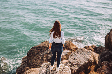 s face is sitting on the stones near the sea. The view is attrac