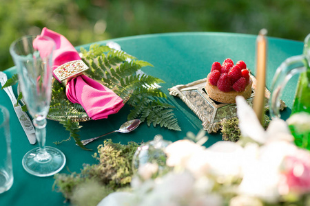 覆盆子甜点表设置。婚礼装饰在魔法森林为一对恋人。粉红色和绿色颜色